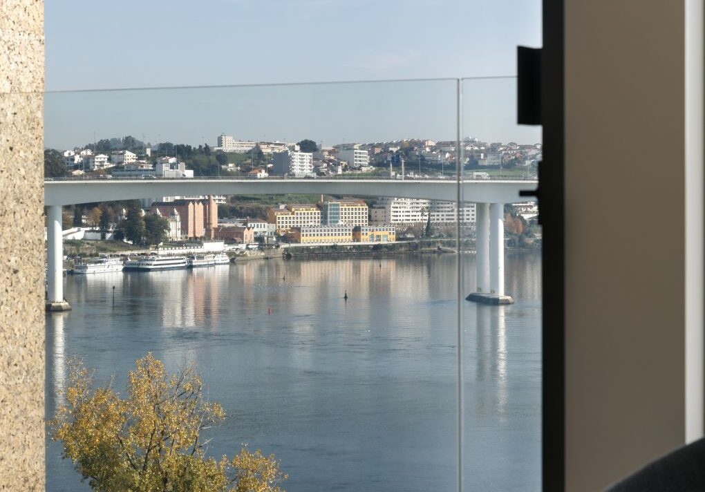 Vista do Rio Douro a partir de um imóvel, com ponte, edifícios e embarcações às margens do rio, no Porto, Portugal.