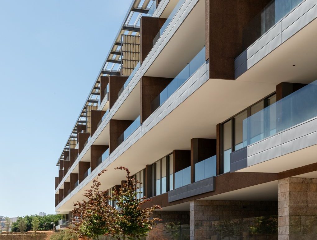 Fachada contemporânea do Projeto Rio Douro, com amplas varandas envidraçadas, revestimento em pedra e arquitetura moderna.
