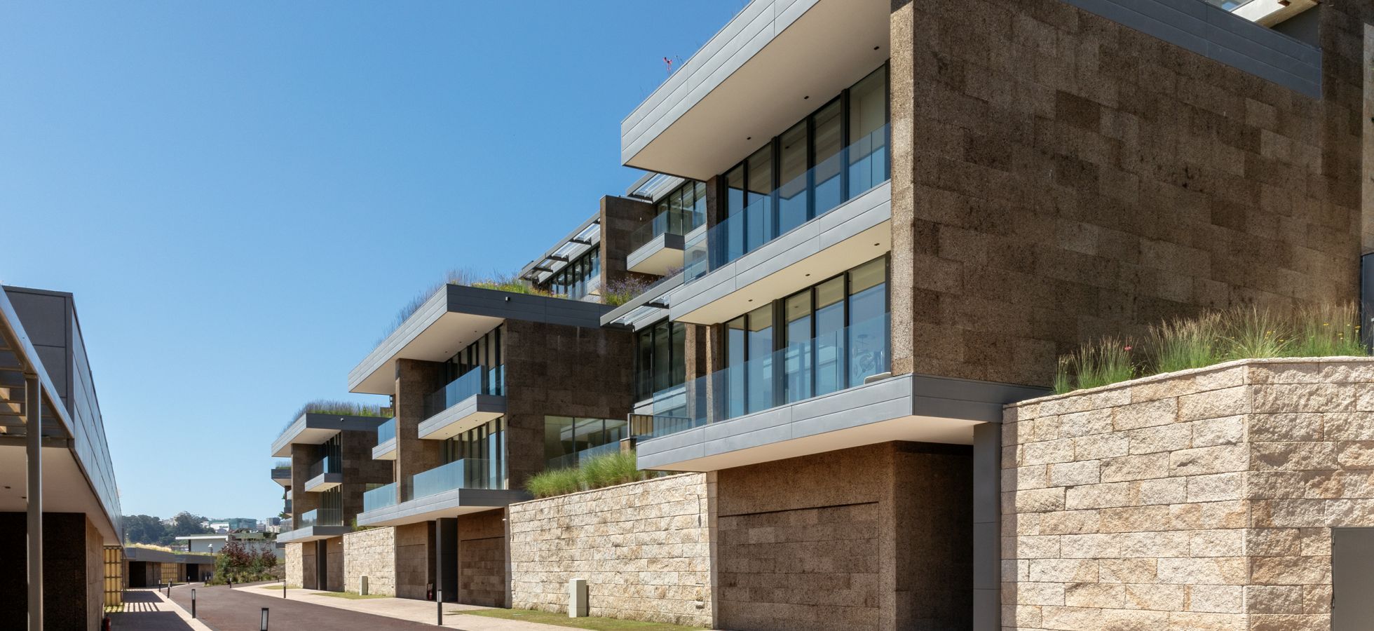 Projeto Rio Douro com apartamentos de arquitetura contemporânea, amplas varandas envidraçadas e revestimento em pedra.